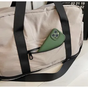 Detail view of travel duffel bag showing front zipper pocket and sturdy black straps.