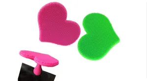 Heart-shaped silicone facial cleansing brush with soft bristles and suction cup base.