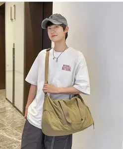 Detailed view of the large capacity canvas messenger bag worn by a model in an indoor scene.