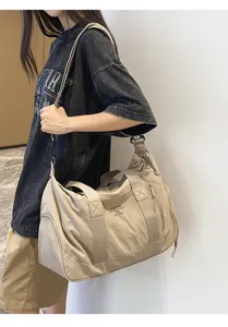 Detailed view of the large capacity beige canvas travel duffel bag worn by model outdoors.