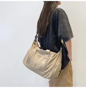 Large capacity canvas messenger shoulder bag in beige, stylish travel and gym gear detail shot.