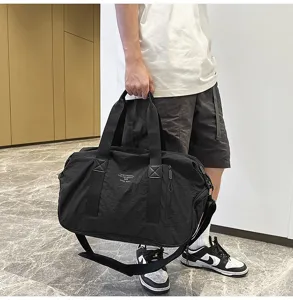 Detailed close-up view of the black travel duffel bag carried by a model indoors.