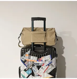 Detailed view of the khaki travel duffel bag placed on suitcase showing durable fabric.