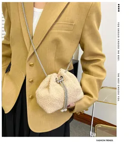 Beige plush drawstring bucket bag with chain strap and pearl detail for women daily use.
