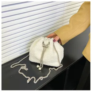 White plush bucket bag detail view, soft furry texture with silver chain strap and pearl decor.