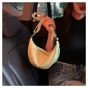 Detail shot of light green nylon crescent shoulder bag, casual style lifestyle in car interior.