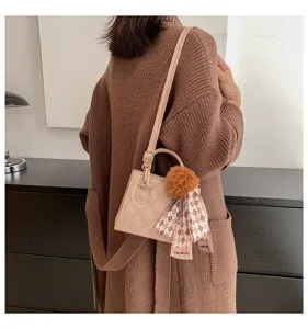 Detailed view of the stylish quilted shoulder handbag with plush pom-pom and ribbon accent.