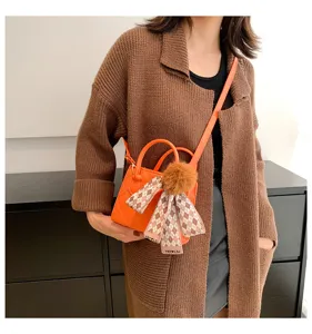 Trendy orange mini crossbody tote bag with chic plaid ribbon scarf and fluffy pom-pom charm.