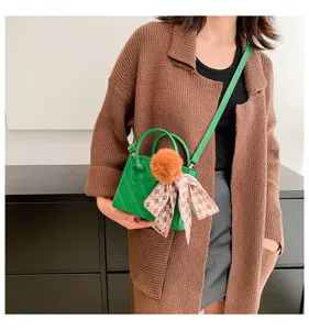 Green mini quilted top handle shoulder bag with fluffy ball charm and chic plaid ribbon detail.