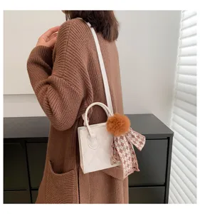 Chic quilted mini handbag detail, featuring a cute pom-pom charm and stylish scarf.
