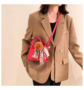 Chic quilted pink mini crossbody handbag with cute fluffy ball and decorative ribbon scarf.