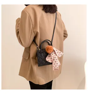Minimalist black quilted crossbody handbag with furry ball and plaid scarf charm for women.