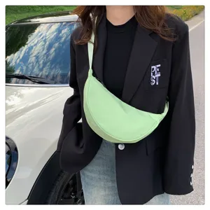 Detailed shot of a light green nylon crescent crossbody dumpling bag worn outdoors.