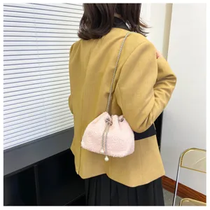 Detail shot of pink plush drawstring bucket bag featuring chain strap and pearl decor.