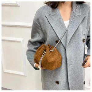 Detail view of a stylish brown plush bucket bag with chain strap and pearls in daily use.