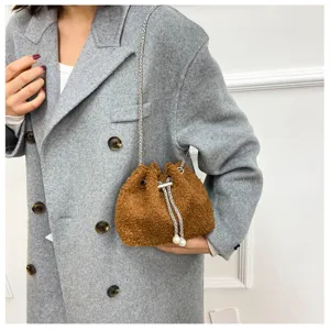 Detail view of brown plush bucket bag featuring chain strap and pearl drawstring closure style.