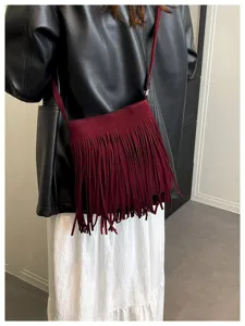 Detailed view of a stylish wine red suede fringe crossbody bag, perfect for autumn outfits.