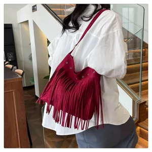 Detailed view of women's red suede fringe shoulder bag showcasing texture and tassel design.