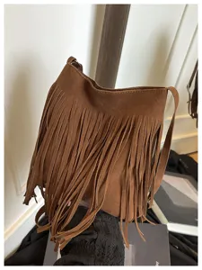 Close-up detail of a brown suede shoulder bag featuring long soft fringes and a strap.