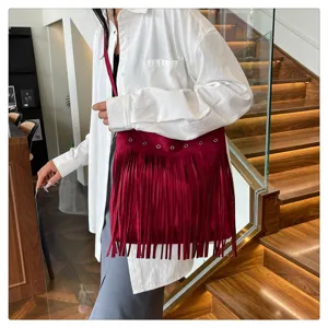 Detailed view of the red suede fringe shoulder bag, showcasing metal eyelets and large capacity.