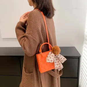 Orange crossbody shoulder bag for women, stylish small square tote bag with cute fuzzy ball charm.