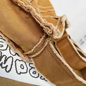 Gros plan des détails du sac bandoulière en toile effilochée style rétro vintage.
