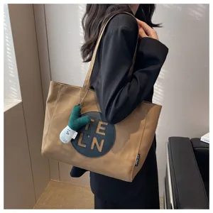 Large capacity brown canvas tote bag for women, stylish shoulder handbag with cute pendant.