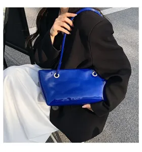 Glossy blue patent leather shoulder bag detail view, chic underarm bag for fashion wear.