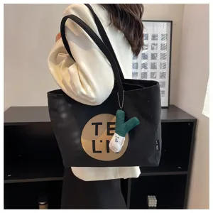 Black canvas tote bag for women, large capacity shoulder handbag with cute plush pendant.