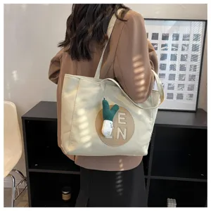 Korean style large capacity canvas tote bag for women with embroidery letters and cute pendant.