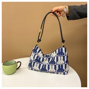 Canvas underarm bag detail showing blue white cartoon rabbit pattern and black shoulder strap.