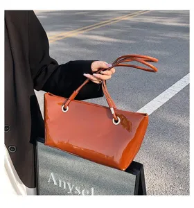 Glossy patent leather tote bag for women, stylish brown shoulder bag with metal ring accents.