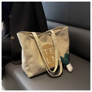 Canvas tote bag detail, beige fabric with round leather patch, casual daily shoulder handbag.