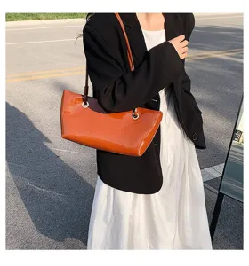 Detail shot of brown patent leather underarm tote bag, stylish everyday women handbag scene.