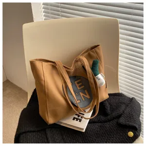 Detail view of the stylish brown canvas tote bag with letter patch and cute charm.