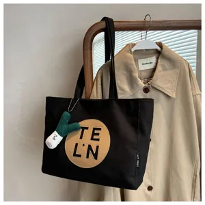 Women large capacity canvas tote bag with stylish letter patch and cute pendant for daily use.