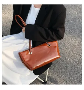 Detail shot of the glossy patent leather brown shoulder underarm tote bag, highlighting texture.