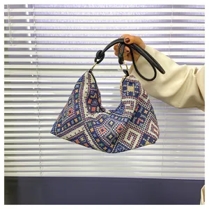 Detailed view of retro ethnic pattern woven underarm shoulder bag with black strap and texture.