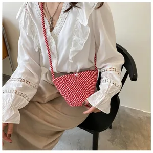 Detailed view of the stylish red woven crossbody bag with pearl closure and braided strap.
