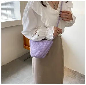 Close-up detail of a chic purple woven bucket bag styled with a white blouse, nice look.