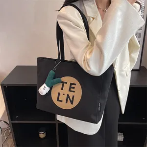 Black canvas tote bag for women, large capacity shoulder handbag with letter patch and charm.