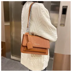 Detailed view of brown crocodile pattern shoulder bag worn on shoulder, elegant design.