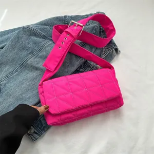 Bright pink quilted crossbody puffer bag with wide strap and chic denim background.