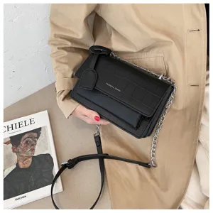 Detailed view of the black faux crocodile leather crossbody bag with chain strap and style.