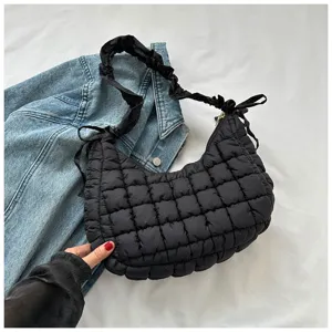 Detail view of a trendy black quilted puffer hobo bag with chic gathered shoulder strap design.