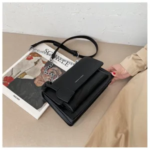 Black crocodile pattern leather shoulder bag detail, featuring metal chain and flap design.
