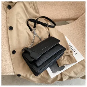 Detailed view of the black crocodile pattern chain crossbody bag with metal hardware and flap design.