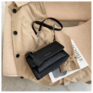 Details of the black textured PU leather crossbody bag with chain strap and chic flap design.