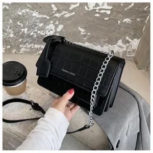 Black crocodile pattern crossbody bag detail, featuring metal chain strap and flap design.