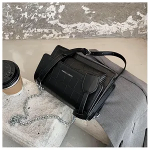 Women black faux leather crocodile pattern crossbody bag with chain strap and flap design.